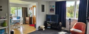 a living room with a television and a desk at Marg's on the Corner in Kumara
