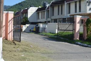 an empty street with a fence and houses at The Cozy Flat by UWI in Hope Pastures