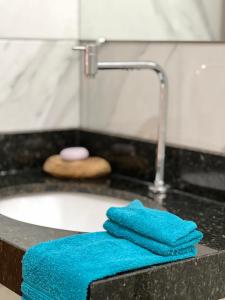 two blue towels sitting on a counter next to a sink at Casa Mazaratto - Hospedagem in Manhã