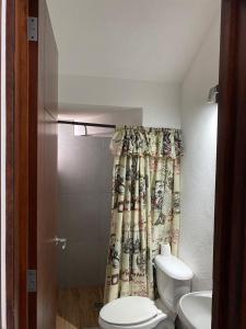 a bathroom with a toilet and a shower curtain at Casa Puerta Paraíso in Tepic +16 photos