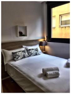 sypialnia z dużym białym łóżkiem i oknem w obiekcie Casas Apartamentos Gracia w Barcelonie
