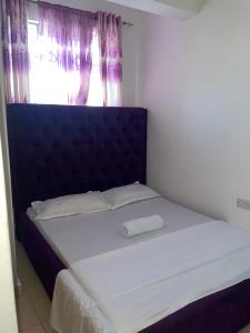 1 cama con cabecero azul y ventana en The Cozy Cove, en Mombasa