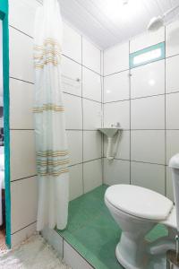 a bathroom with a toilet and a shower curtain at SunriseBelaVista Pousada e Flats in Paraty