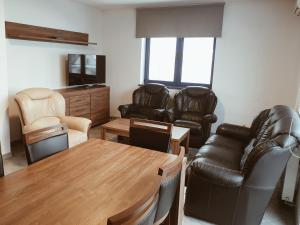 a living room with leather furniture and a wooden table at Go2Krynica - Zielony PitStop in Krynica Zdrój