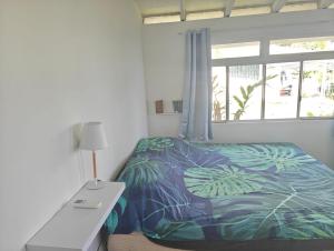 una camera da letto con un letto, una scrivania e una finestra di Manohei Lodge- Chambre indépendante Pamatai a Faaa