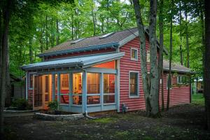 una pequeña casa roja en el bosque en Dollybrook 4 Pet Friendly Community Pool Groups Welcome, en Fennville