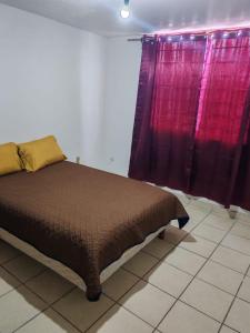 a bed sitting in a room with purple curtains at Casa de tres habitaciones por infonavit constituyentes in Uruapan del Progreso