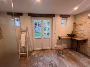 a bathroom with a door and a sink and a stool at La Petite Ecluse in Tanlay