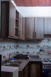 Una cocina con gabinetes de madera y un fregadero. en Lumière de Ville, en Kigali