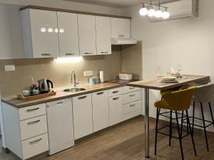a kitchen with white cabinets and a table with chairs at Apartman Matea - Self Check-in in Osijek