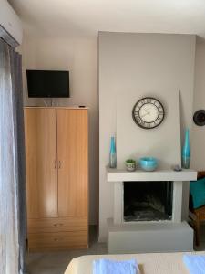a living room with a clock and a fireplace at Olympia's Seaside Lefokastro in Lefokastro +16 photos