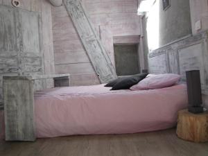 un letto con lenzuola e cuscini rosa in una stanza di Gite De Charme Auvergne Cab'âne a Brousse