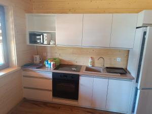 a small kitchen with white cabinets and a sink at Domki z klimatyzacją in Prażmowo
