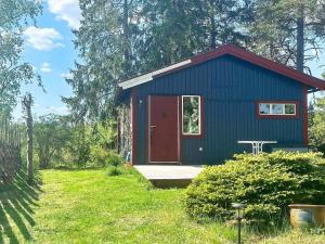 a blue house with a red door in a yard at 4 person holiday home in HERRäNG-By Traum in Herräng