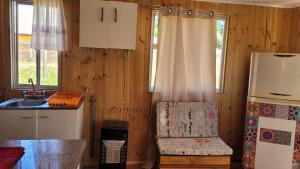 a kitchen with a refrigerator and a chair in it at Cabañas Lomas de Putagan in Linares