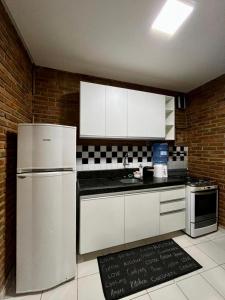 a kitchen with white appliances and a brick wall at Casa Praia do Frances in Marechal Deodoro