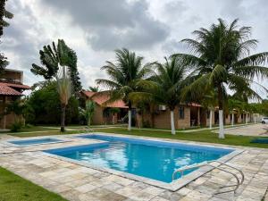 a swimming pool in front of a house with palm trees at Casa Praia do Frances in Marechal Deodoro