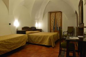 a bedroom with two beds and a table and chairs at Hotel Gufo in Bormio