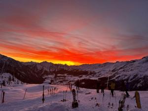 un gruppo di persone in piedi sulla neve al tramonto di Rifugio Baita Belvedere a Champoluc