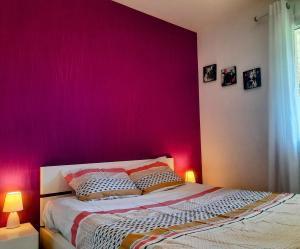 ein Schlafzimmer mit einer rosa Wand und einem Bett mit Kissen in der Unterkunft Les Merisiers - Maison moderne avec jardin in Pornic