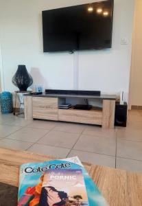 ein Wohnzimmer mit einem TV und einem Buch auf dem Tisch in der Unterkunft Les Merisiers - Maison moderne avec jardin in Pornic
