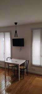 a white table and chairs in a room with windows at Studio moderno al centro di Parigi - République in Paris