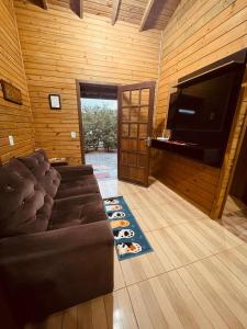 a living room with a couch and a flat screen tv at Cabanas dos Sonhos 2- Barra de Ibiraquera in Imbituba