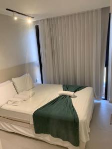a bedroom with a large white bed with a green blanket at Cais Eco Residencia Boutique Beira Mar in Porto De Galinhas +32 photos