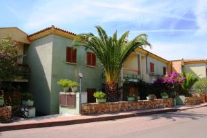 a house with a palm tree in front of a street at Verande Tanca Torre in Isola Rossa