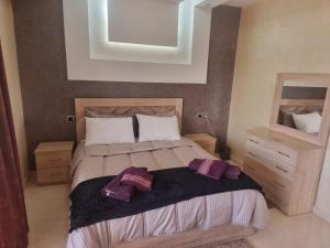a bedroom with a large bed with purple pillows on it at LA PERLE DE L'OCÉAN 2 Appartement de rêve face à l'Atlantique luxe, confort et dépaysement in Akhfennirr +32 photos