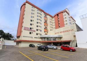 a hotel with cars parked in a parking lot at Hotel Metropolitan Canoas in Canoas