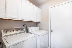 a kitchen with white cabinets and a washer and dryer at Spacious 4BR Home with Pool BBQ & Games in Grand Prairie