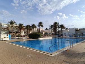a large swimming pool with palm trees and buildings at apartment tenerife south coast in Costa Del Silencio