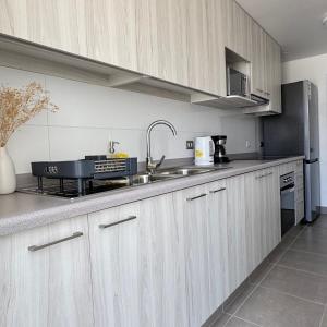 a kitchen with wooden cabinets and a sink and a stove at Departamento in Antofagasta