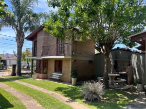 ein Backsteinhaus mit einer Bank und einem Baum in der Unterkunft Cabañas Los Aromos in Embalse