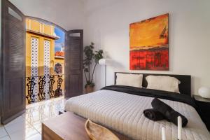 a bedroom with a bed and a painting on the wall at Spanish Penthouse Historic Mansion Private Patio in San Juan