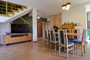 a dining room with a table with chairs and a television at Mazurska Sarenka in Wiartel