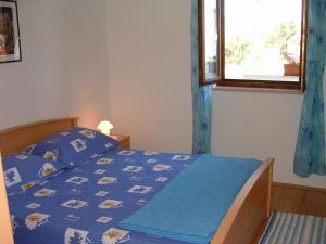 a bedroom with a bed with a blue comforter and a window at Apartments Dinka in Mirce