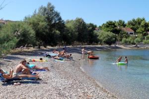 a group of people sitting on a beach in the water at Apartments Dinka in Mirce +25 photos