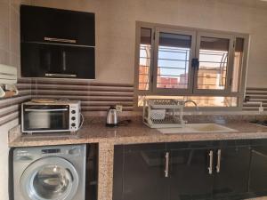 a kitchen with a washing machine and a microwave at LA PERLE DE L'OCEAN 1 là ou' le confort rencontre l'infini de l,atlantique et la beaute des couchers de soleil in Akhfennirr