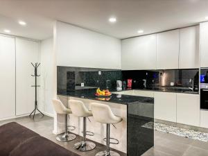 a kitchen with white cabinets and a counter with stools at Bragança Holiday Home new apartment with 2 bedrooms private parking in Bragança