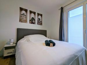 a bedroom with a white bed with a book on it at Le chaleureux, T2 avec balcon in Roanne