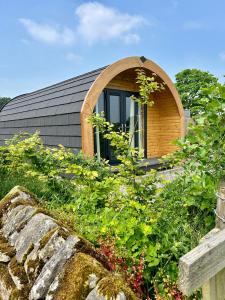 a small house with a window on top of a garden at Luxury Glamping Pod - Garthside Farm Holidays in Brampton
