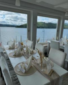 a long table with white chairs and a large window at Strandhaus Edersee - Kaminzimmer, Seeblick, Badestrand, Seeterrasse in Waldeck