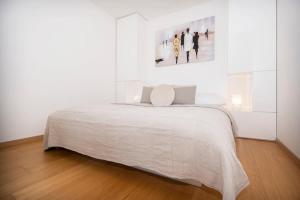 a white bedroom with a bed and a painting on the wall at Luxury 1BDRM on the 28th floor in Bratislava