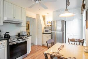 a kitchen with white cabinets and a table and a refrigerator at On the bay in Wellfleet - walk to water! in Wellfleet +22 photos
