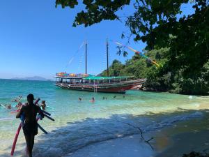 a man walking on the beach with a boat in the water at Casa Lory in Angra dos Reis