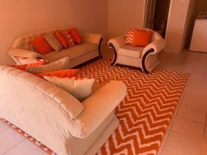 two couches and two chairs in a living room at Lovely 1bedroom apartment with pool in Christ Church