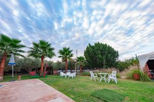 a group of chairs and tables in a yard with palm trees at Villa Baddi Marrakech in Marrakesh