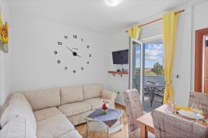 Una sala de estar con un sofá y un reloj en la pared. en Mery's Sunny Pool Apartment - Happy Rentals, en Vodnjan